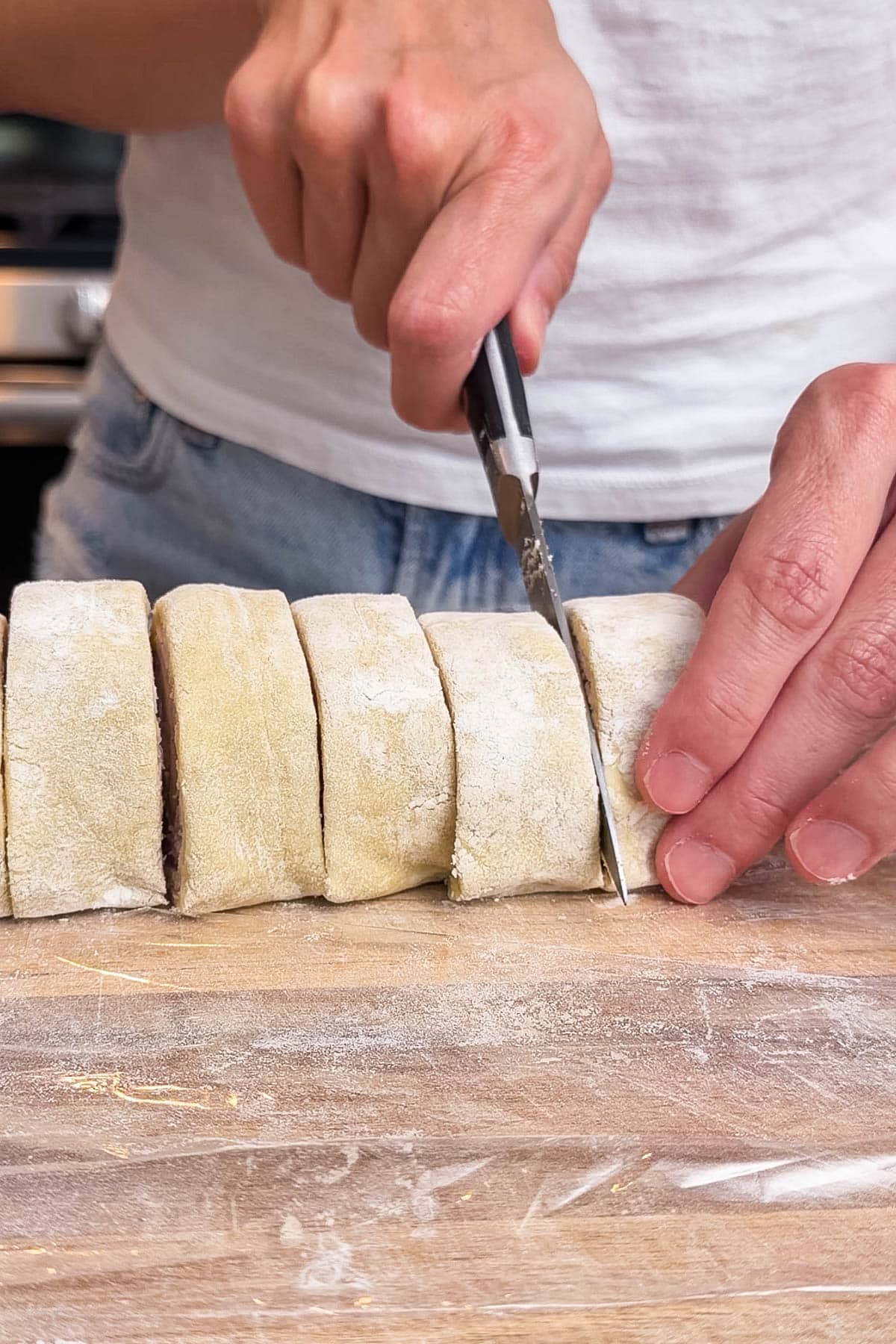 A sharp knife is used to slice the rolled up puff pastry into sections.