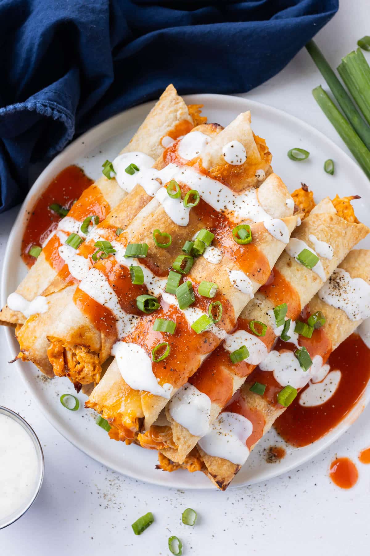Buffalo chicken taquitos that have been baked in the oven are served on a plate for game day.
