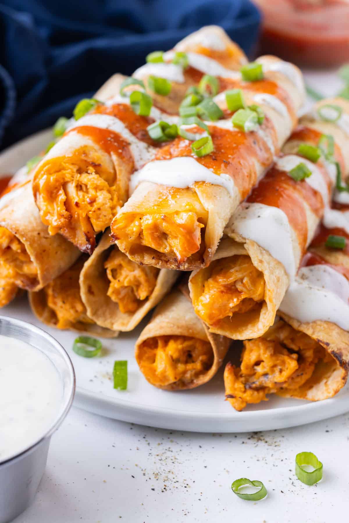 Oven-baked chicken taquitos with buffalo sauce and ranch dressing are served on a dinner plate.