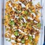 Loaded smashed totchos with cheese, bacon, and crispy tater tots on a baking sheet.