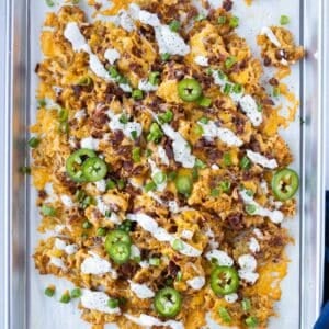 Loaded smashed totchos with cheese, bacon, and crispy tater tots on a baking sheet.