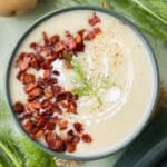 A bowl of Potato Leek Soup with Fennel is served with crispy bacon on top.