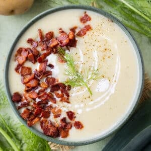 A bowl of Potato Leek Soup with Fennel is served with crispy bacon on top.