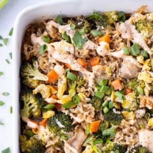 Chicken Fried Rice Bake is in a white baking dish with spicy sriracha mayo sauce drizzled on top.