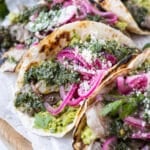Chimichurri steak tacos with pickled red onions and avocado are on a serving tray.