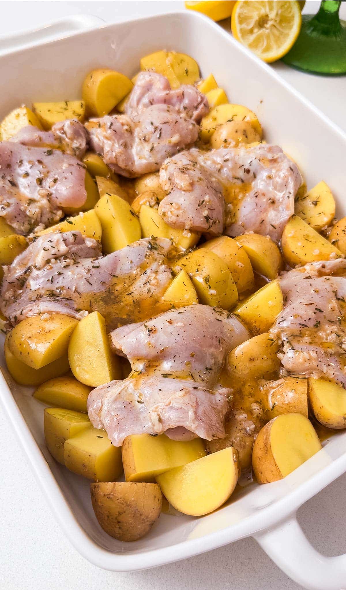 Seasoned chicken is added to a dish with potatoes.