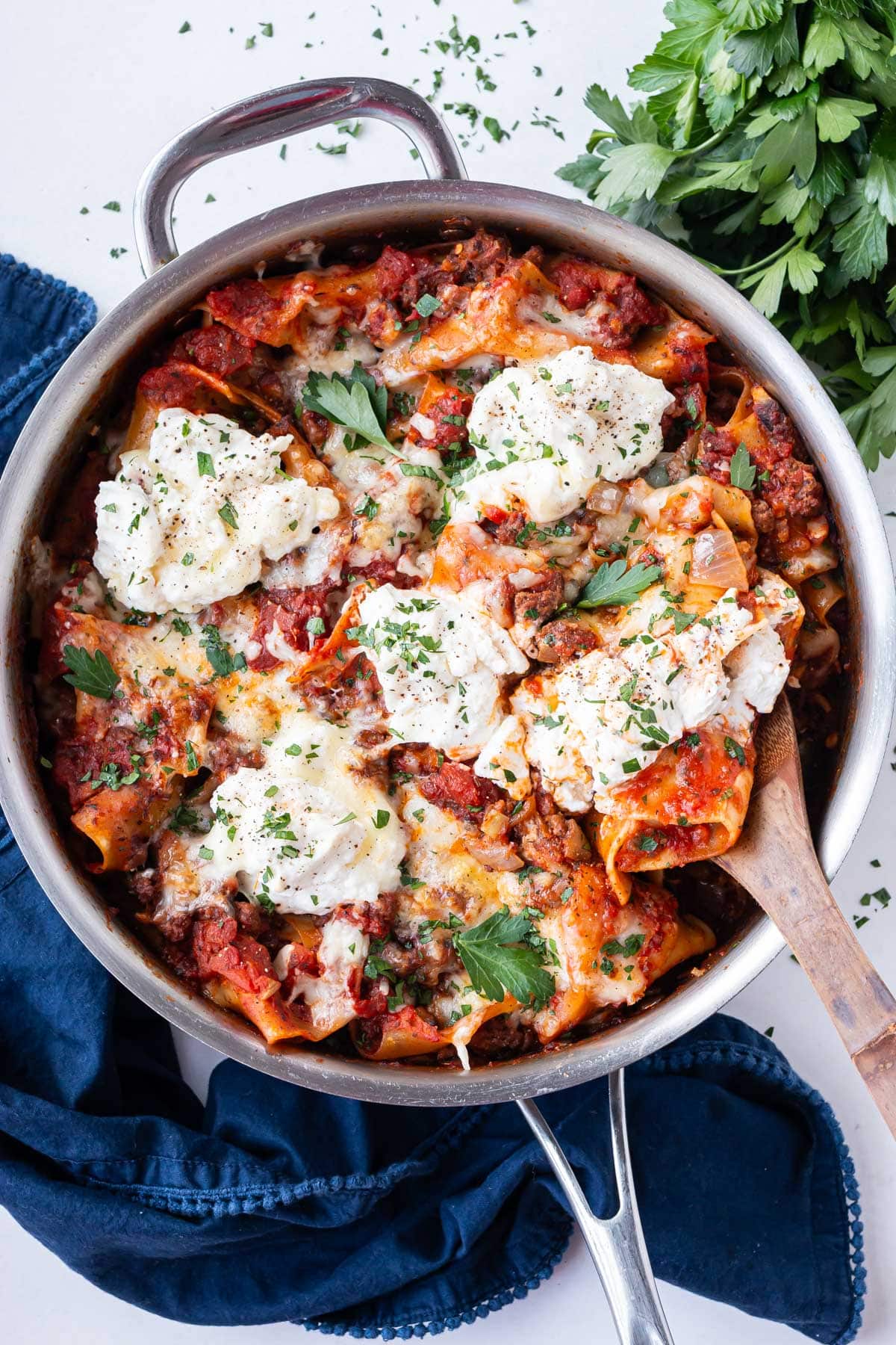 A spoon is scooping up a serving of a one-pot lazy lasagna recipe from a pot with ricotta and beef.