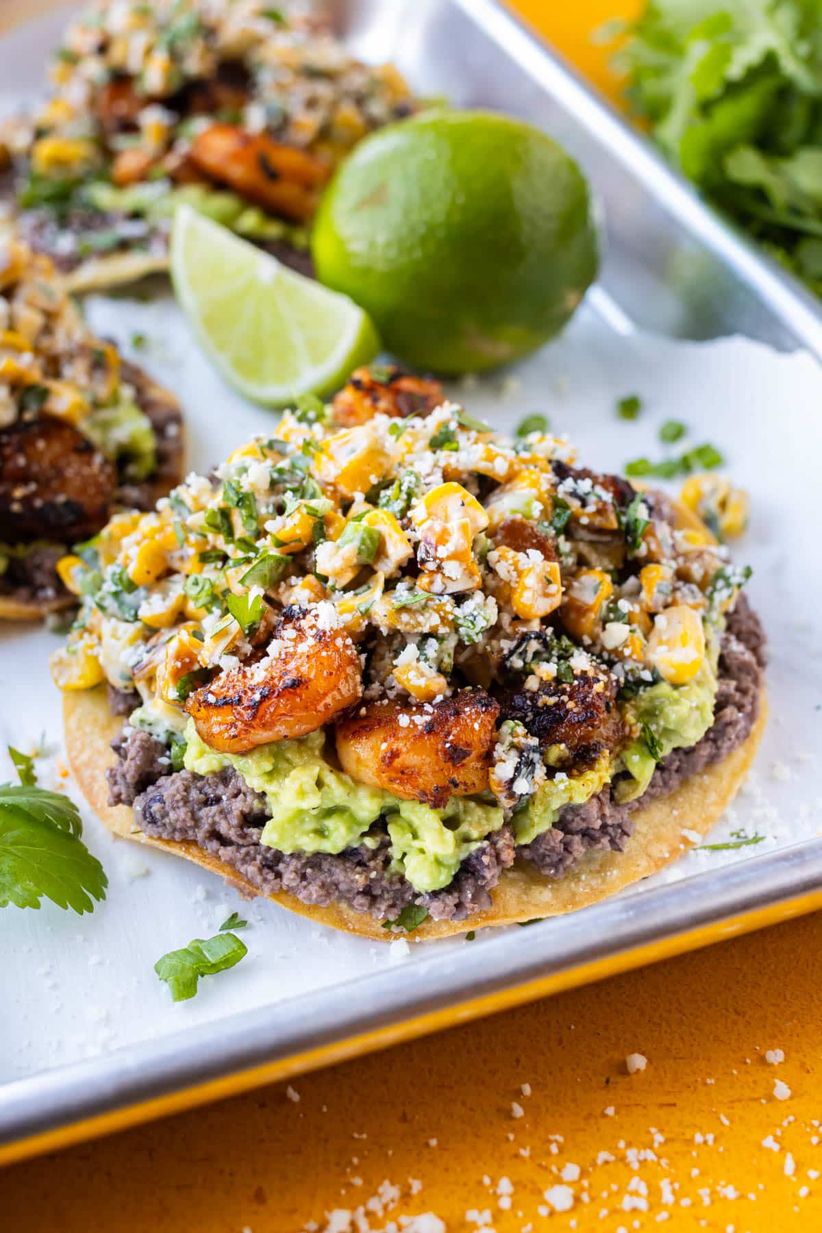 Shrimp Tostadas with black beans, avocado, and Mexican street corn are on a tray for an easy weeknight dinner.
