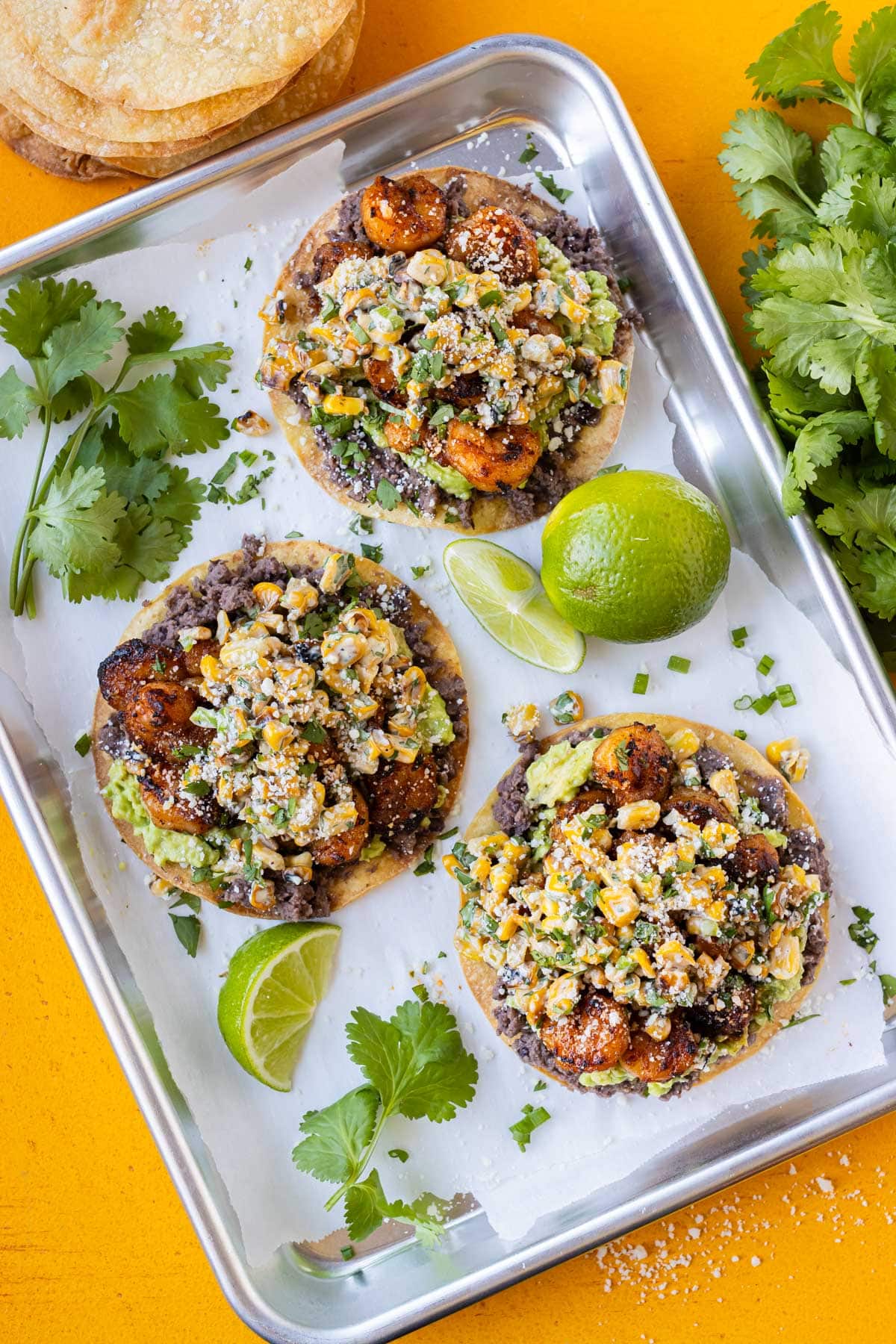 A tray is full of easy shrimp tostadas with corn, beans, and avocado.