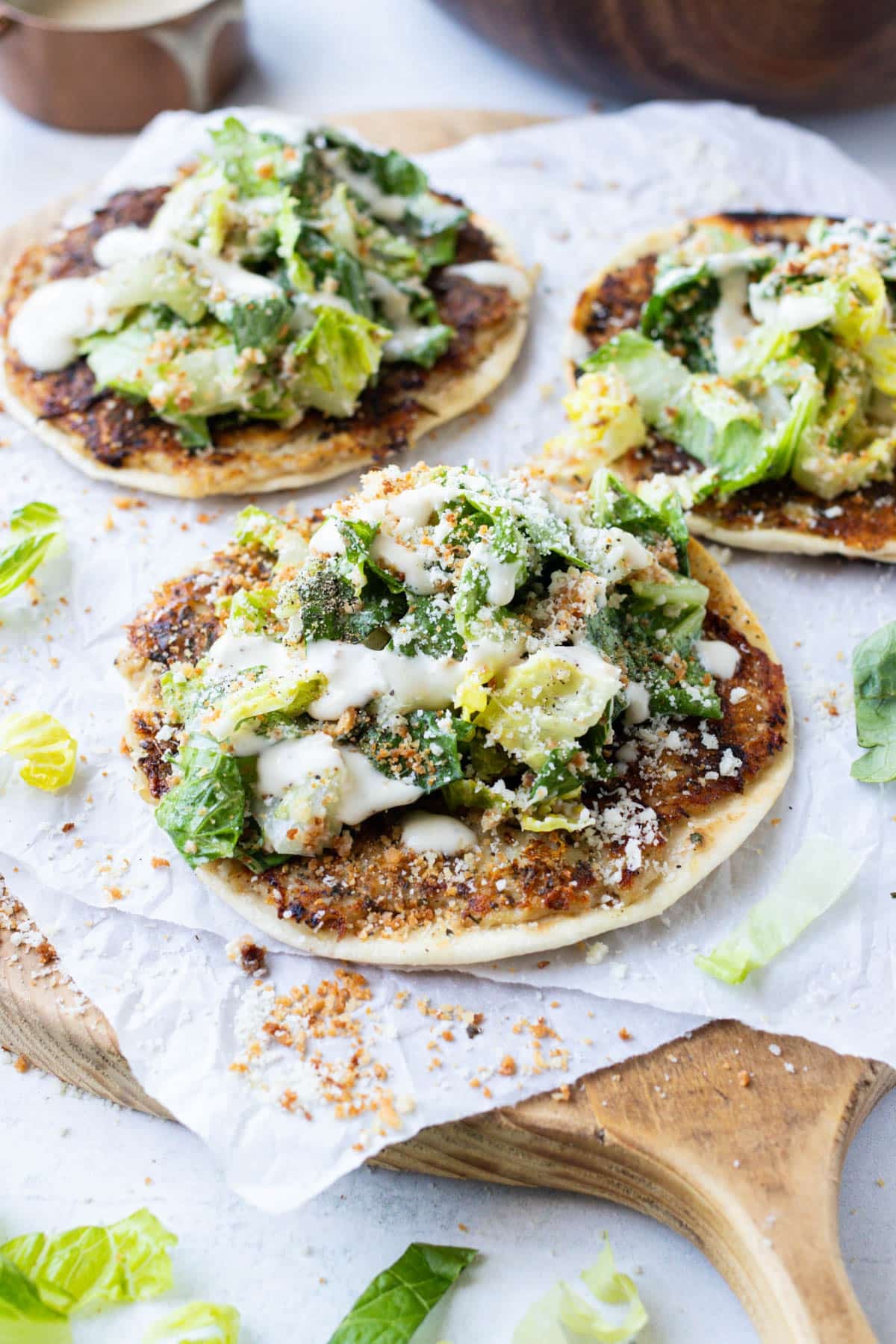 Three chicken caesar smash tacos with crispy parmesan crust and caesar salad on a cutting board