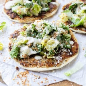 Chicken caesar smash tacos topped with fresh caesar salad on a wooden cutting board