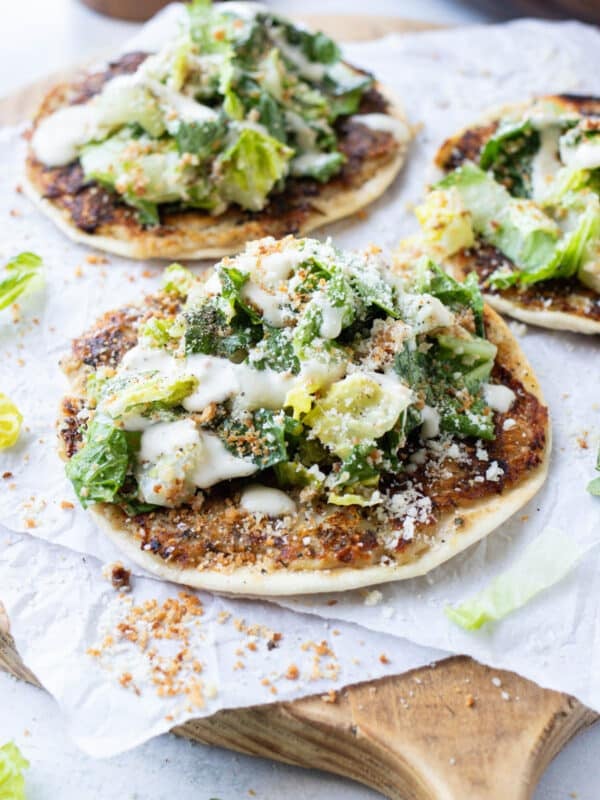 Chicken caesar smash tacos topped with fresh caesar salad on a wooden cutting board