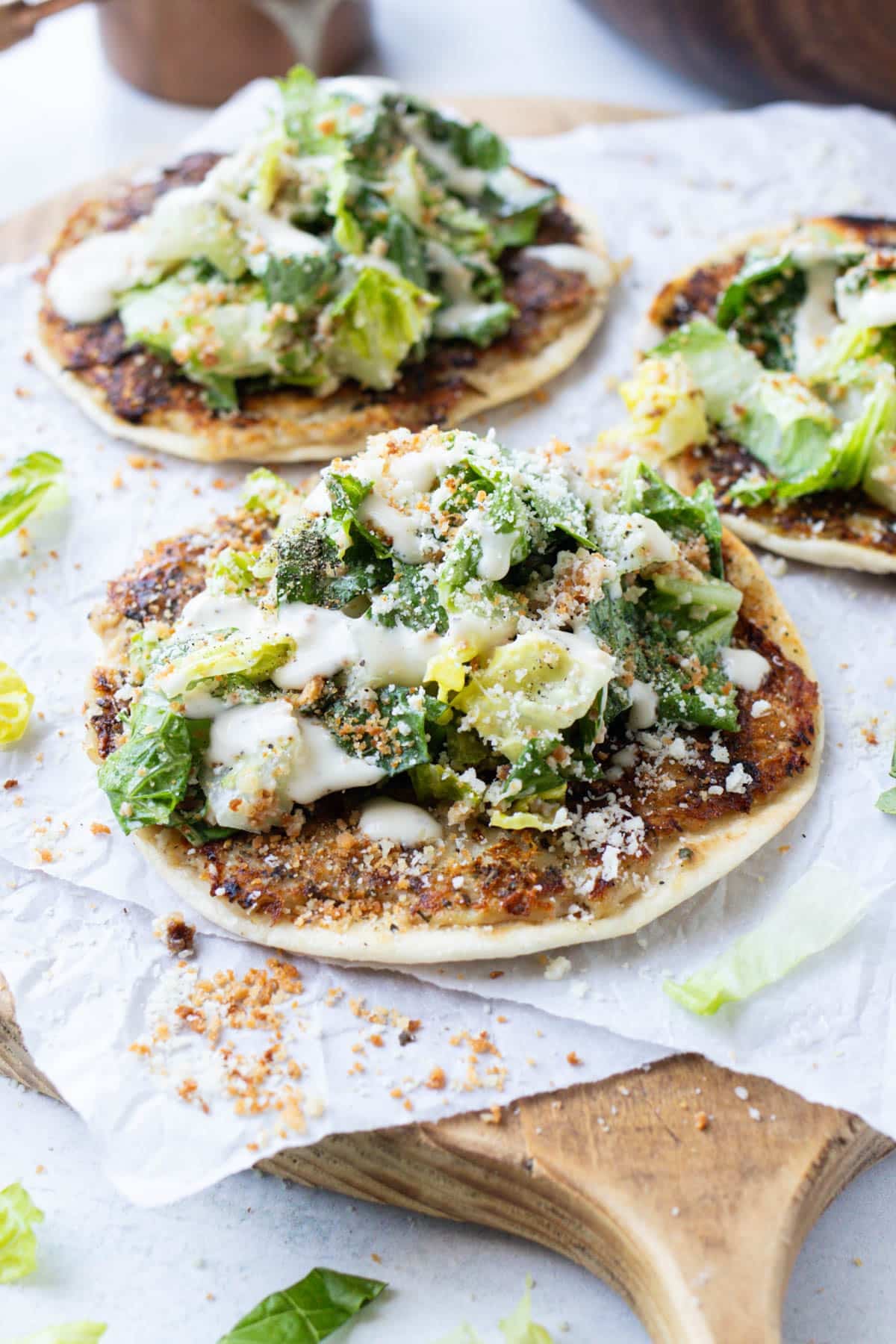 Chicken caesar smash tacos topped with fresh caesar salad on a wooden cutting board