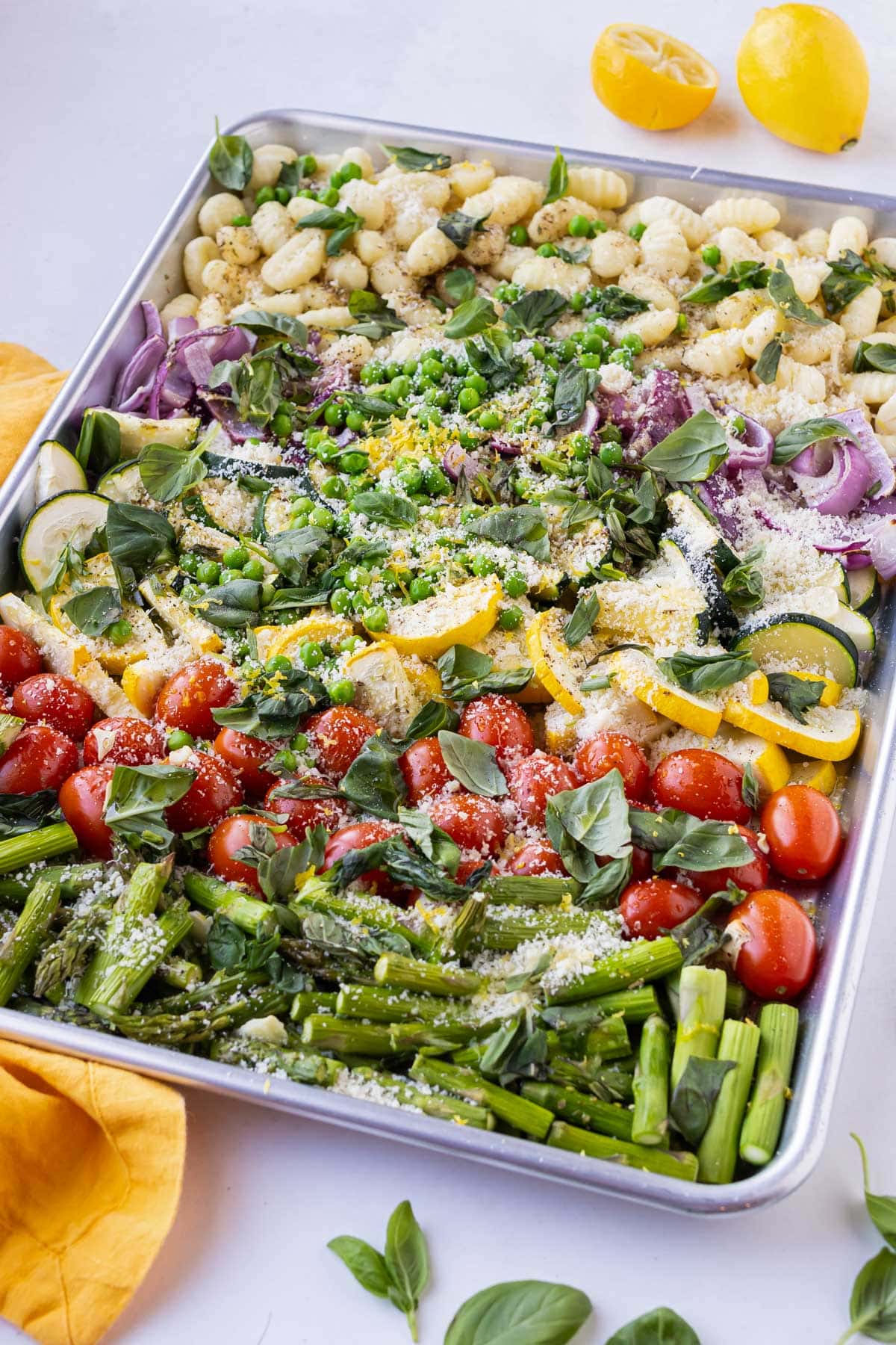 A sheet pan full is full of gnocchi, roasted vegetables, lemon