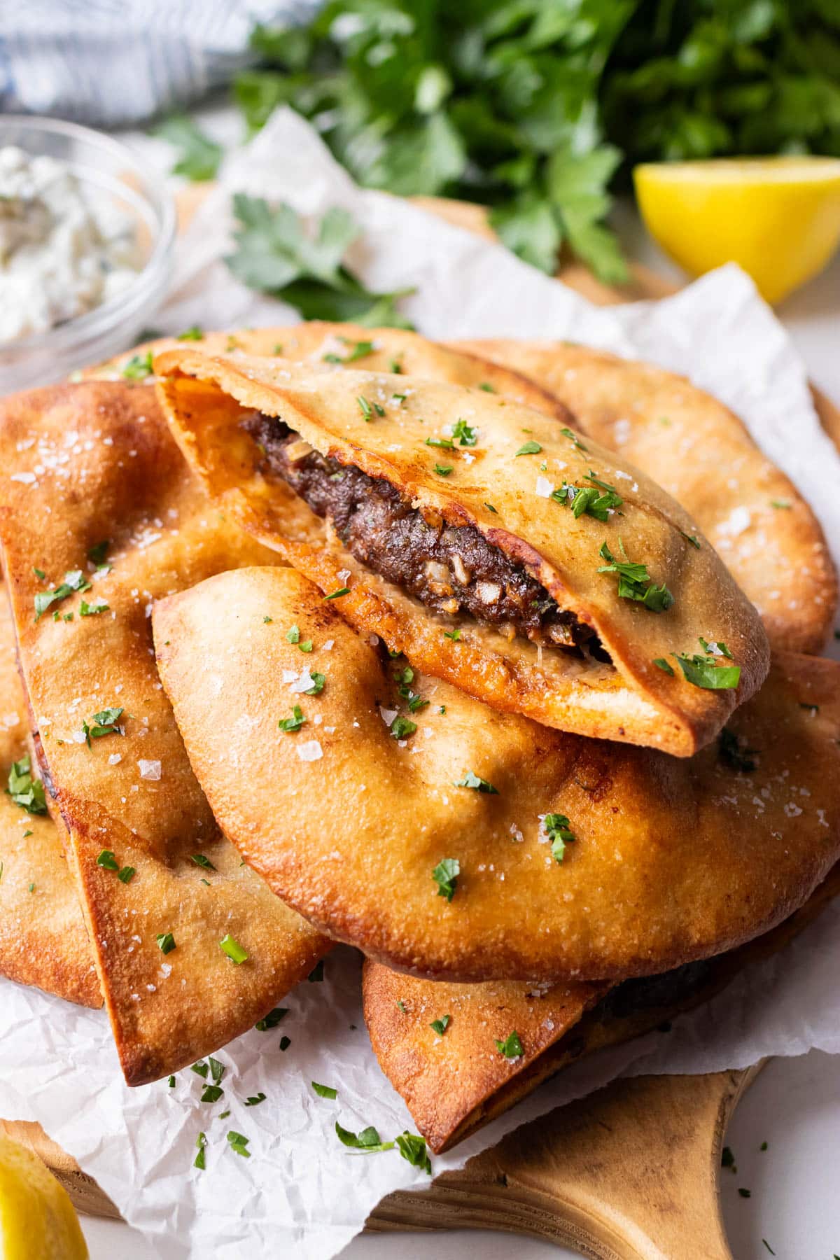 Crispy Lebanese arayes stacked with one cut open showing juicy seasoned beef filling.