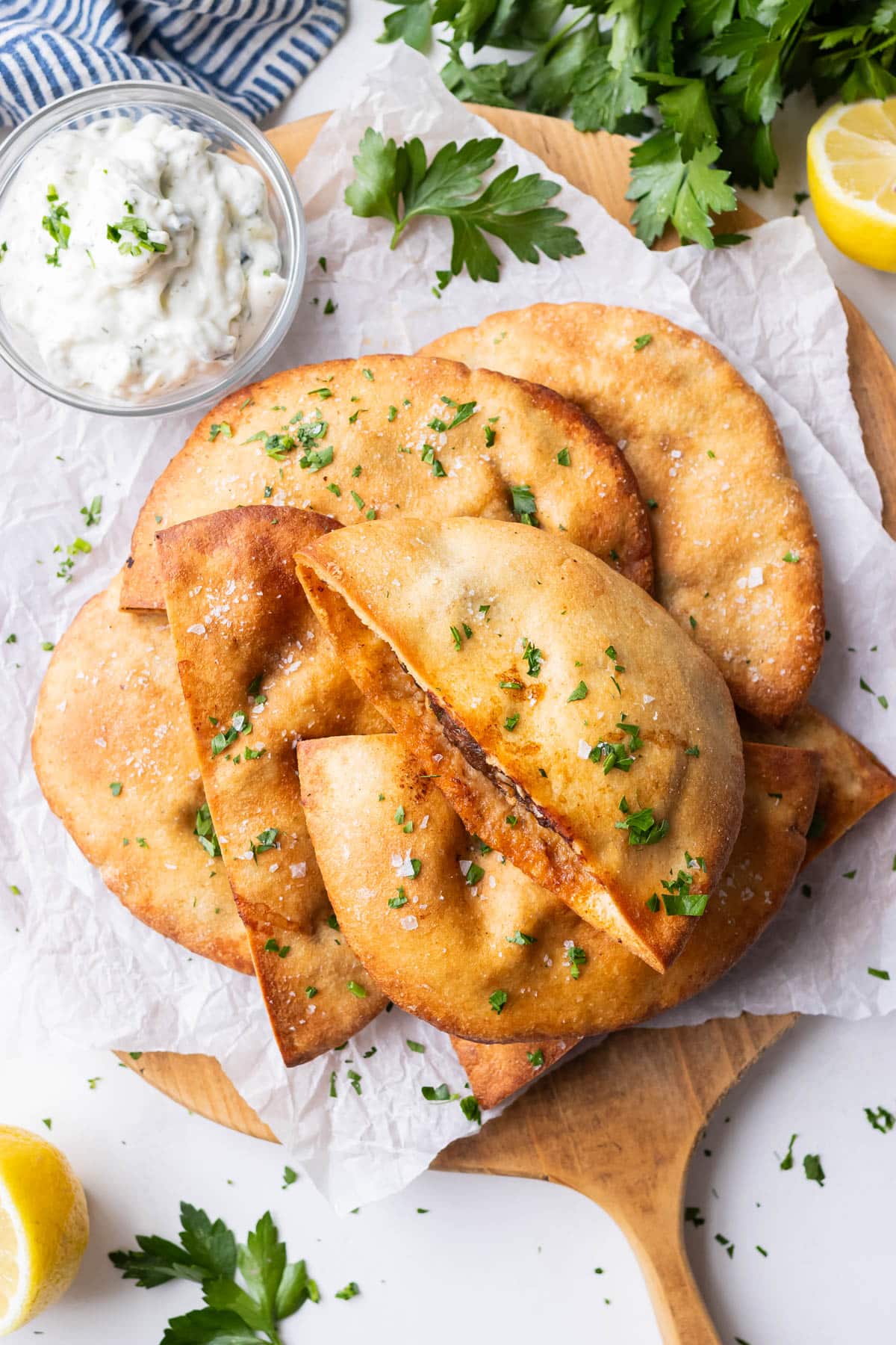 A stack of crispy baked arayes with tzatziki dipping sauce, parsley, and lemon.