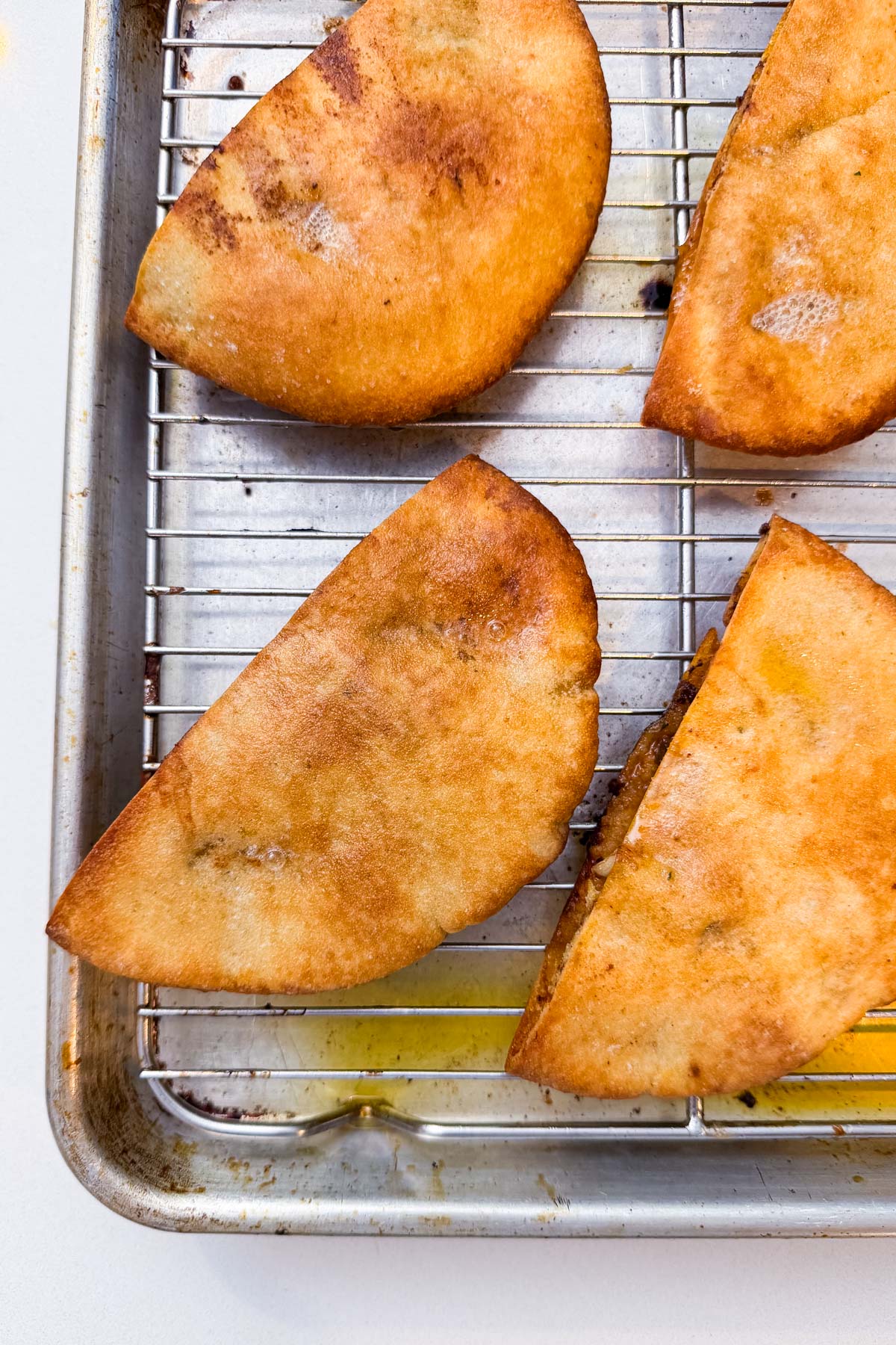 Close-up of golden, crispy baked arayes resting on a wire rack fresh from the oven for Arayes.