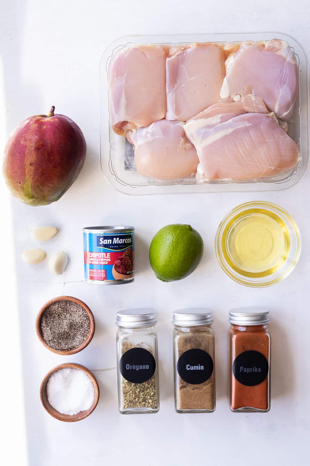 Mango, chicken thighs, chipotles in adobo, garlic, lime, olive oil, salt, oregano, cumin, and paprika as the ingredients for Mango Chipotle Chicken Rice Bowls.