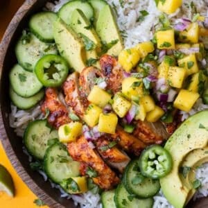 Chipotle mango chicken rice bowls with fresh mango salsa, cucumbers, and avocado.