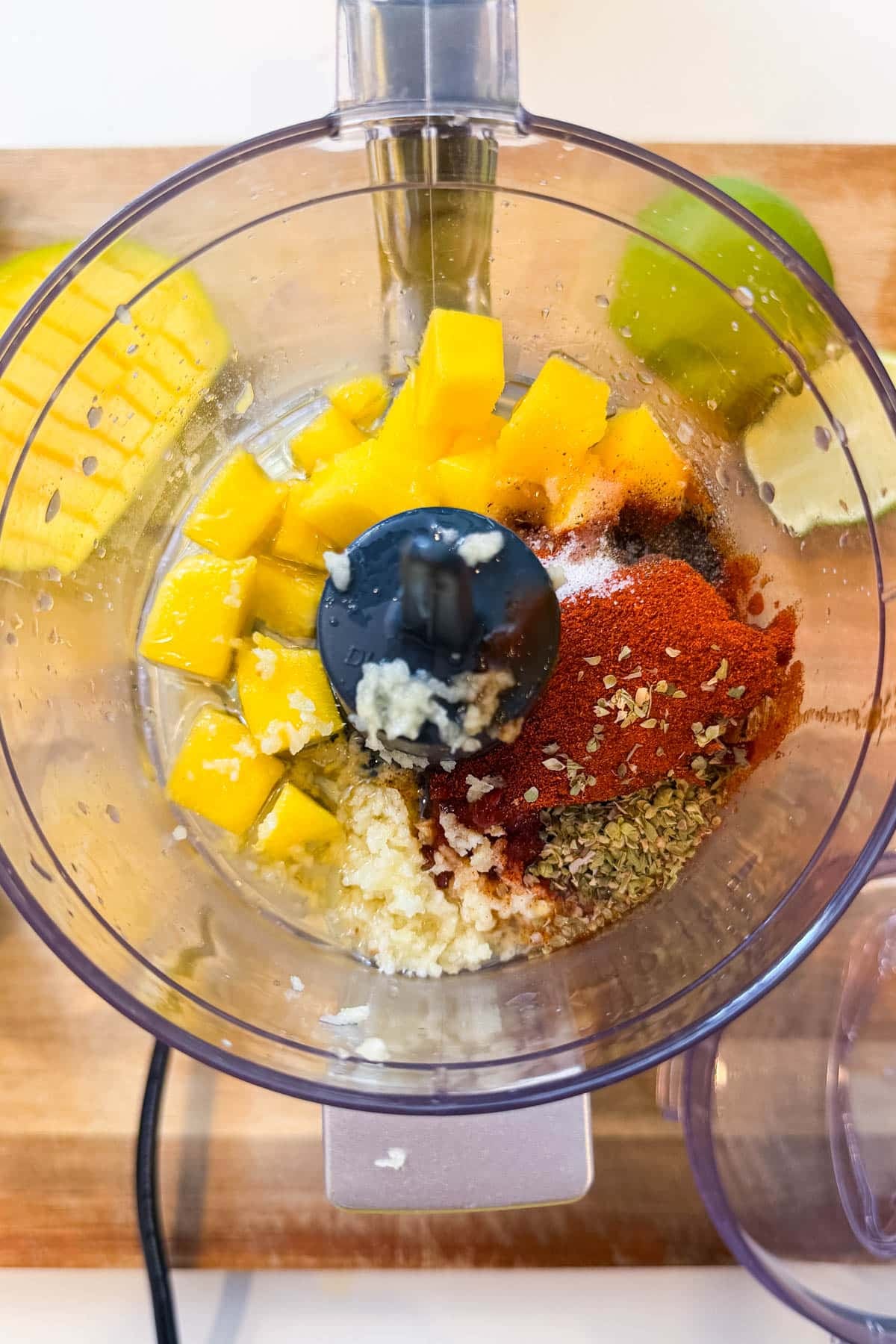 Mango chunks, chipotle peppers, garlic, lime, and spices in a food processor before blending the marinade for Mango Chipotle Chicken Rice Bowls.