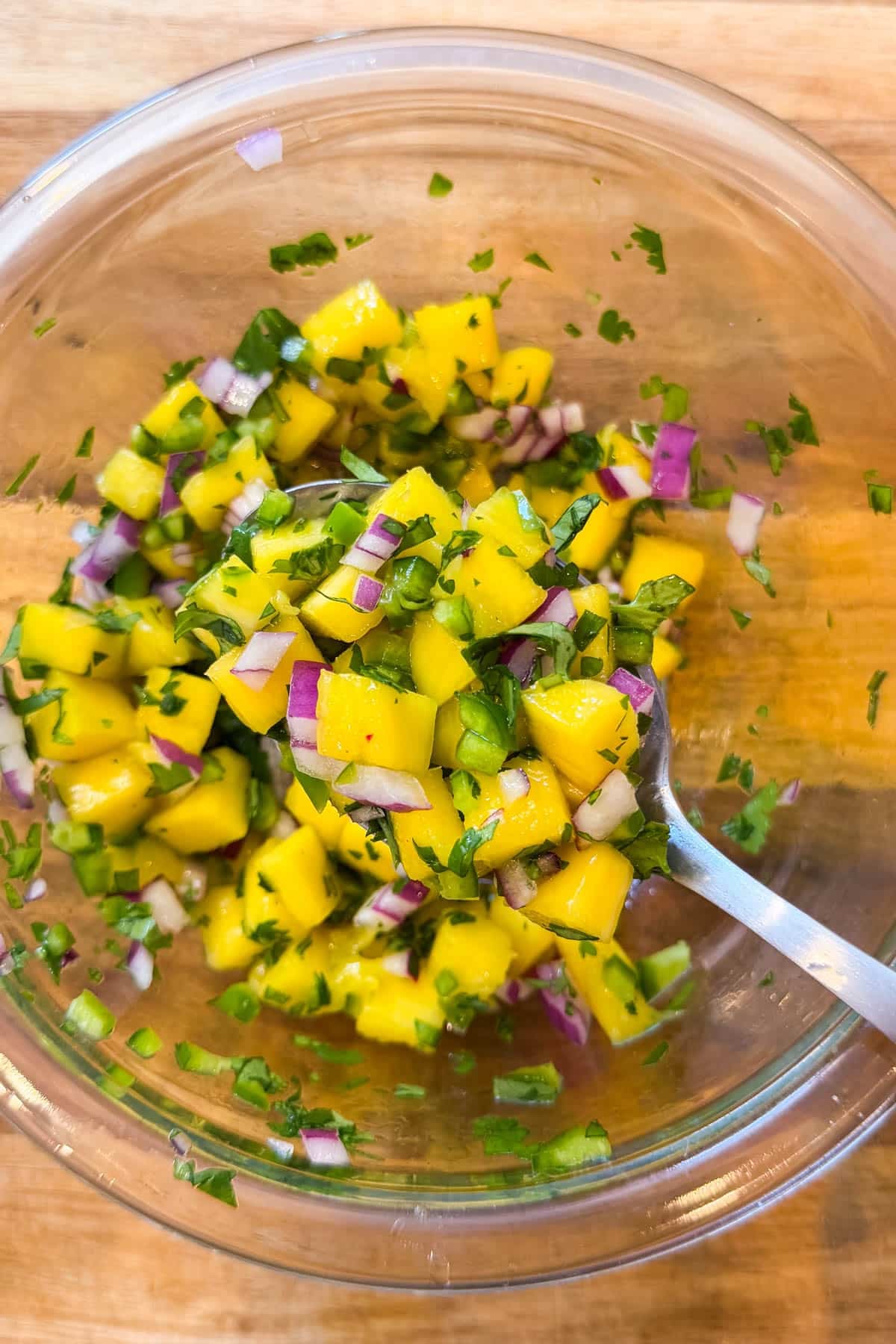 Fresh mango salsa with diced mango, red onion, jalapeño, and cilantro in a glass bowl.