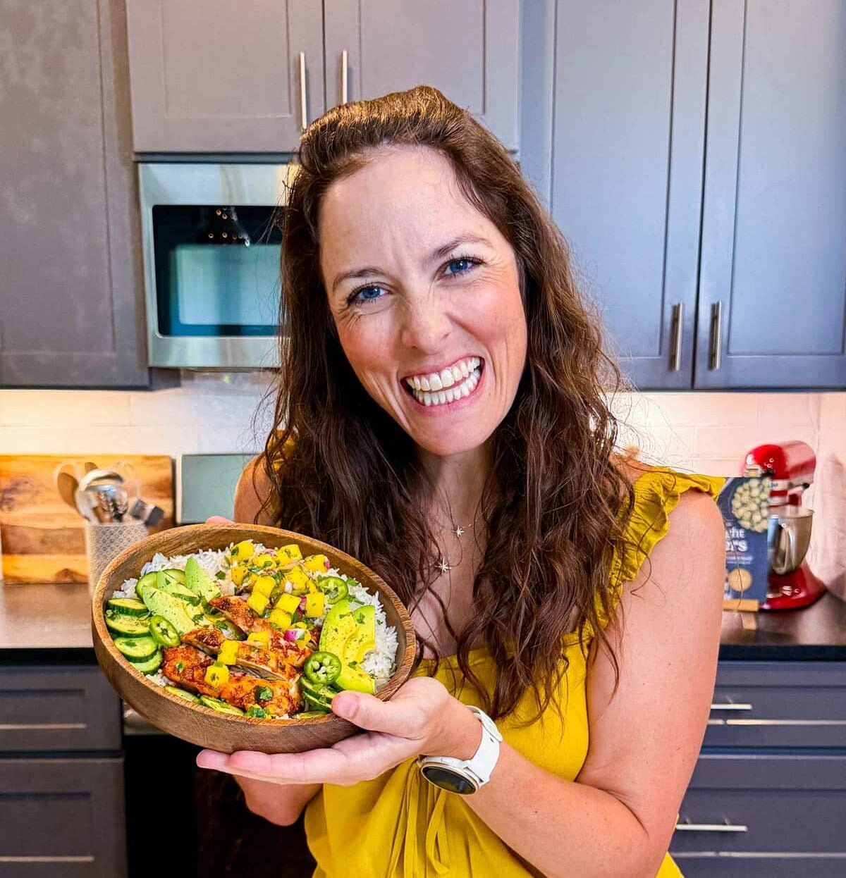 London Lea is standing in her kitchen holding a chipotle mango chicken rice bowl.