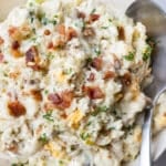 A classic potato salad with bacon is served in a white bowl for a summer bbq.