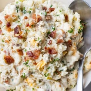 A classic potato salad with bacon is served in a white bowl for a summer bbq.