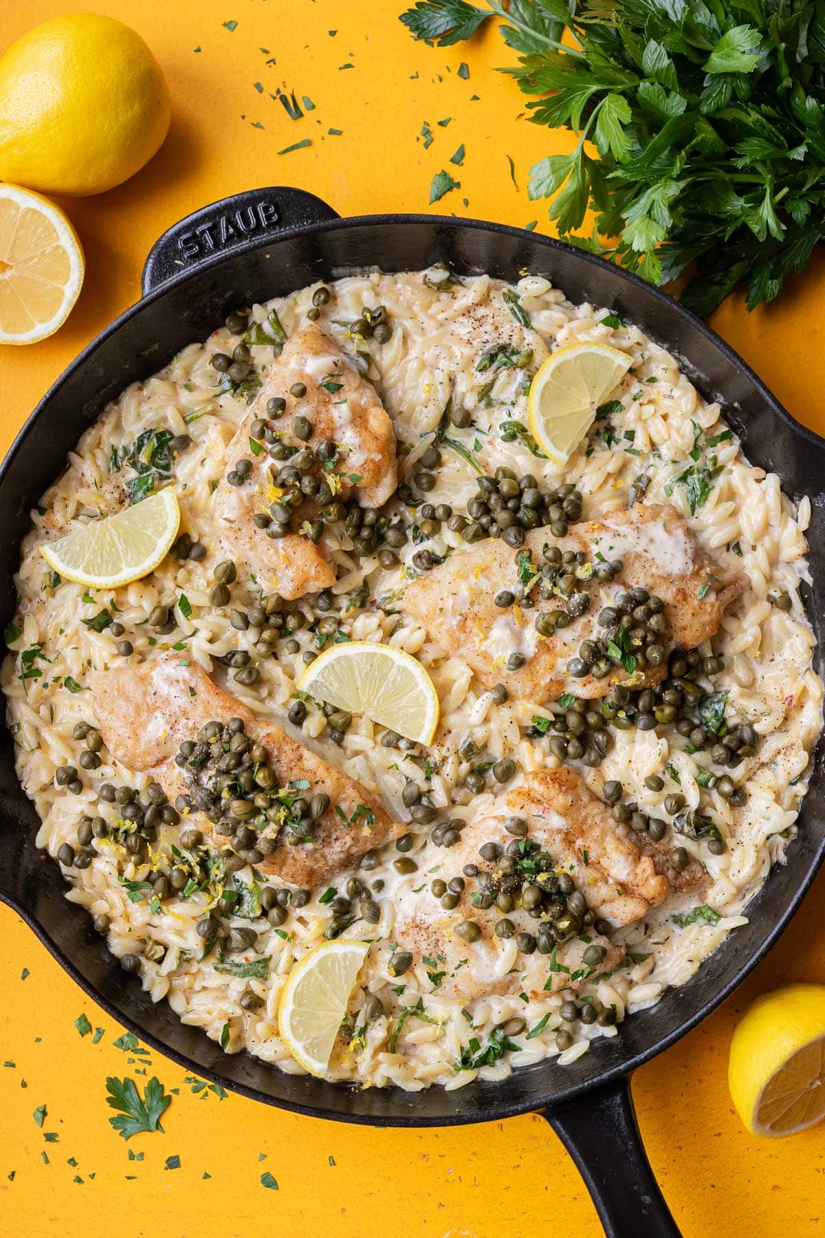 Cod piccata with creamy orzo in a cast-iron skillet for a one-pot meal.