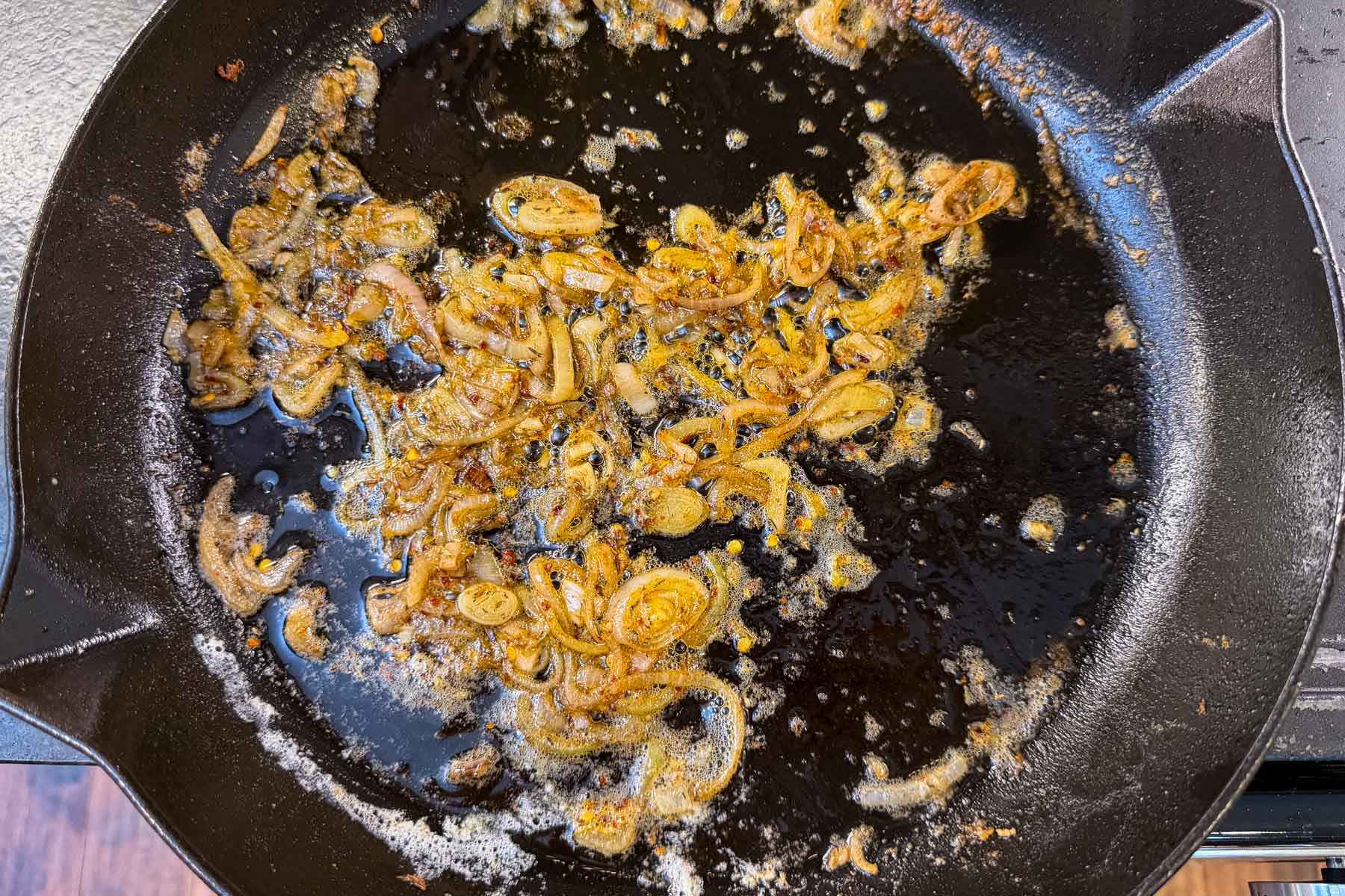 Caramelized shallots cooking in a cast iron skillet to build the piccata sauce base.