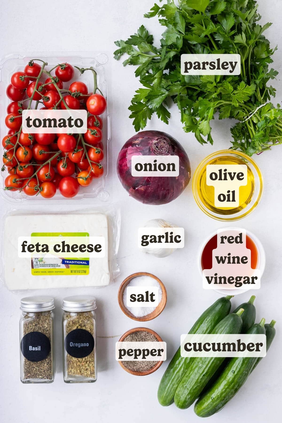 The ingredients for an easy Greek cucumber tomato and feta salad are laid out on a counter.