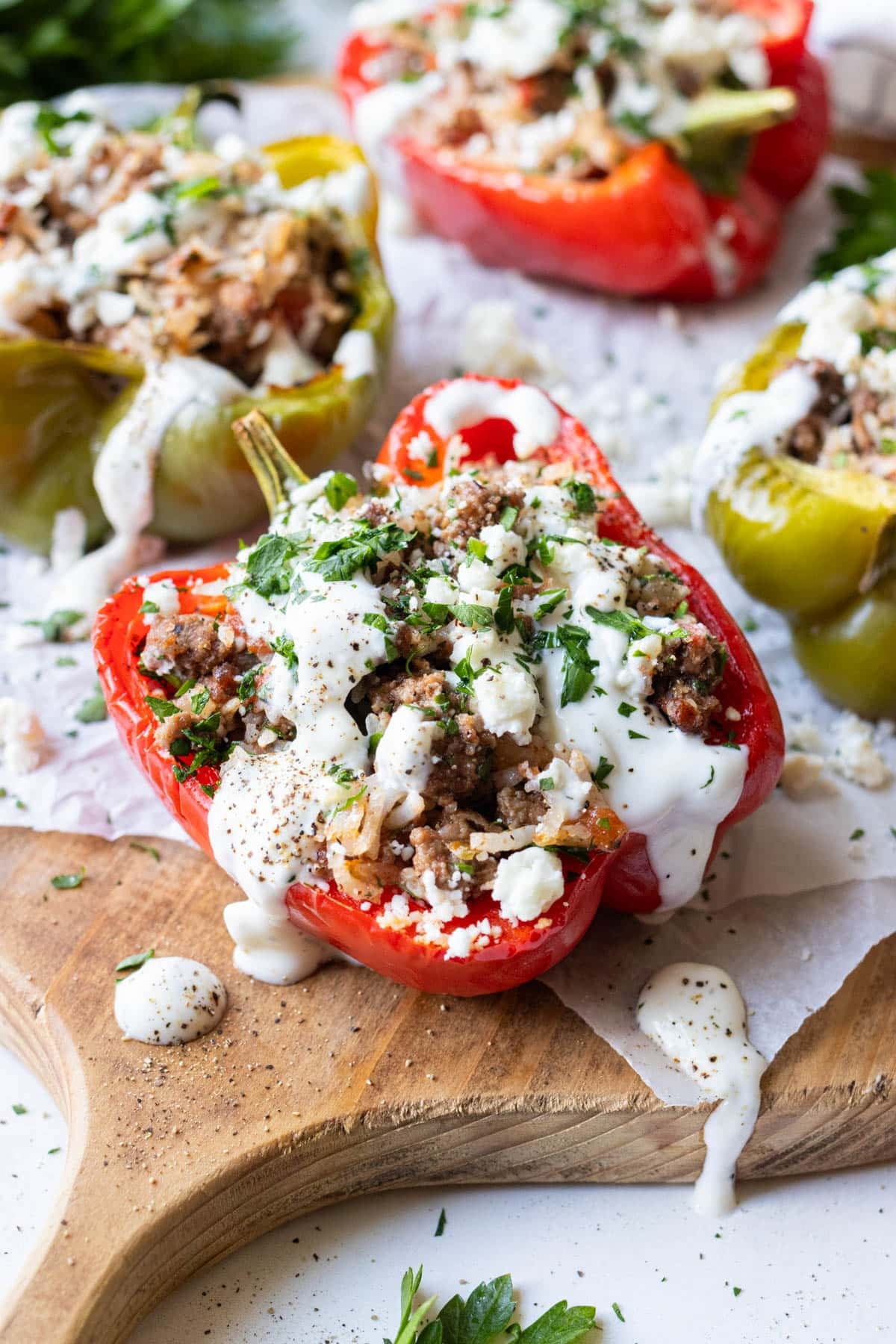 A Greek Stuffed Pepper with tzatziki sauce and feta cheese on top is on a dinner board for serving