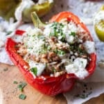 A Greek stuffed bell pepper with a beef and rice filling is served with tzatziki sauce and feta cheese.