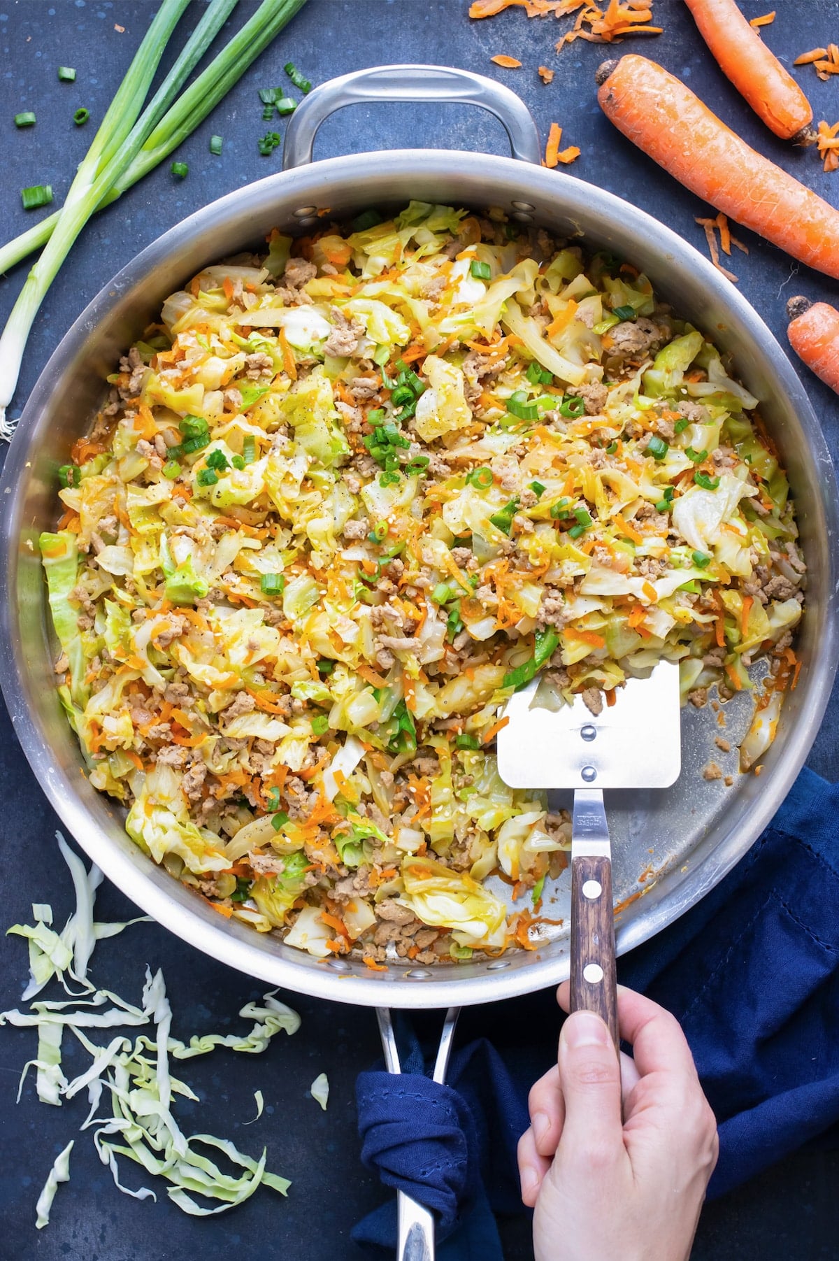 A low-carb and keto egg roll in a bowl recipe is being scooped out of a skillet with a spatula.