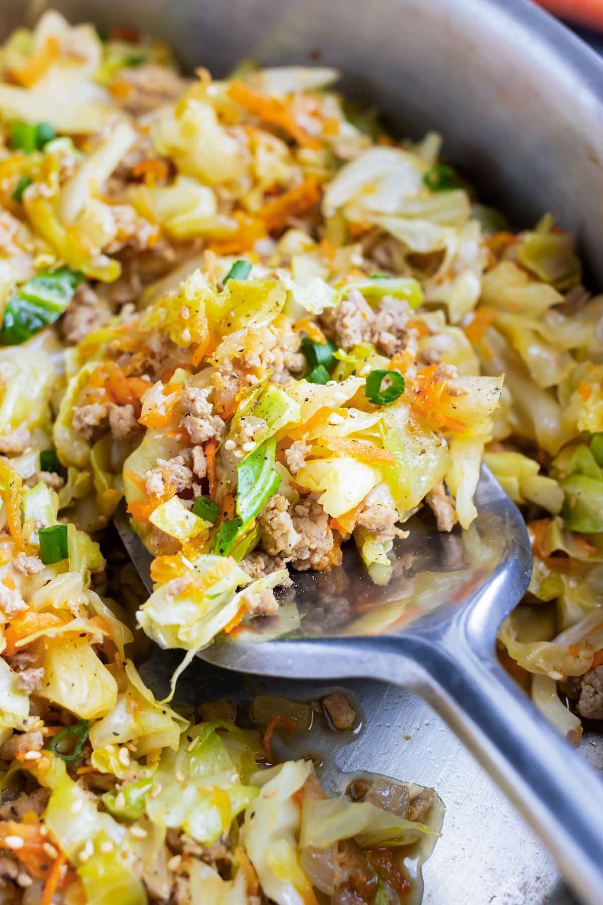 A spatula scoops up a serving of a deconstructed egg roll bowl from a pan.
