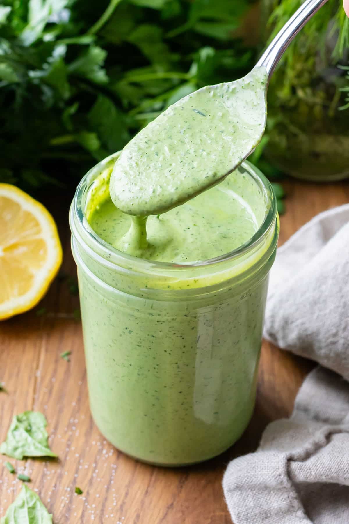 Creamy green goddess dressing in a jar with fresh herbs