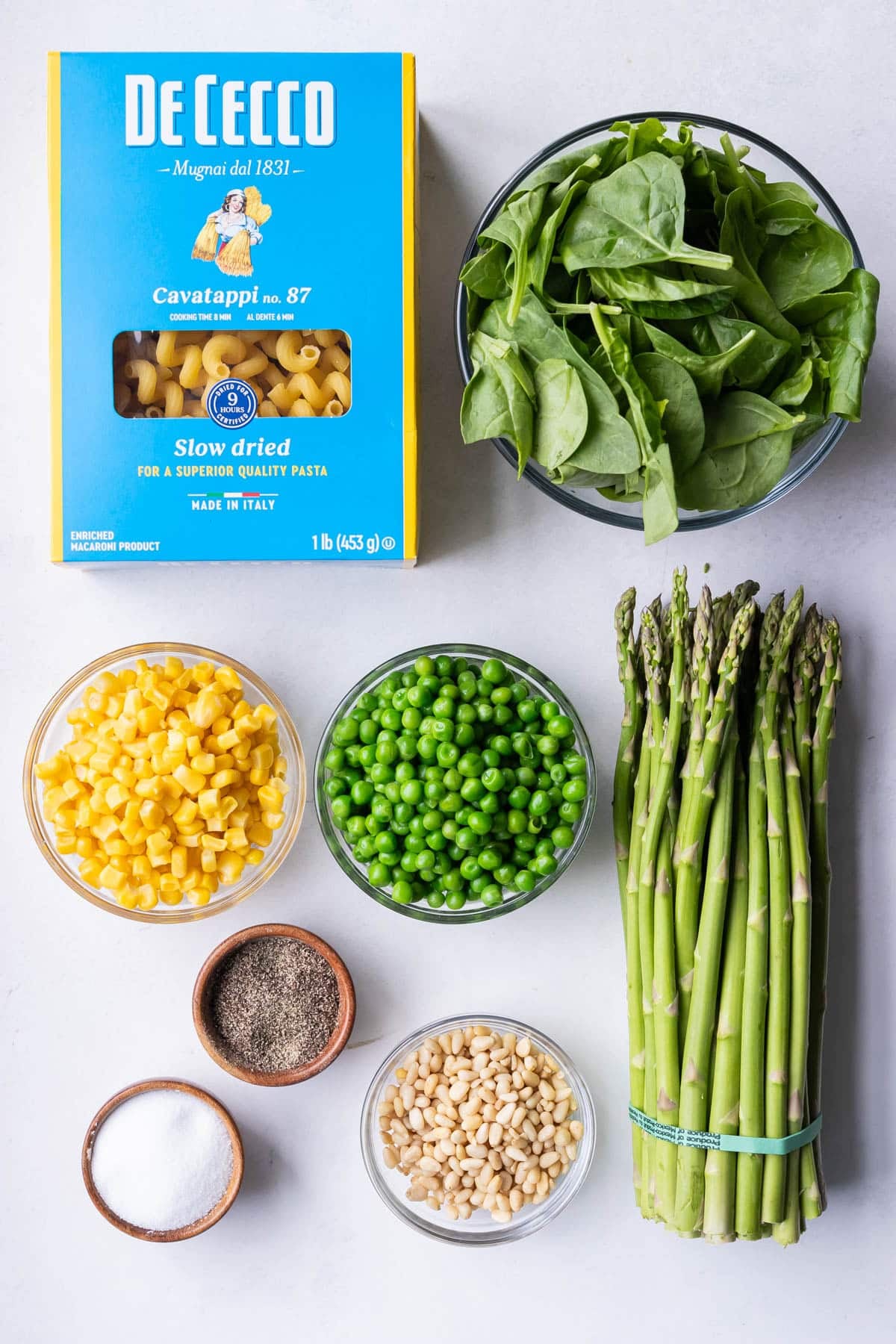 Cavatappi pasta, corn, peas, spinach, asparagus and pine nuts for a green goddess pasta salad recipe.