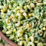 A green goddess pasta salad is served in a wooden salad bowl with asparagus, corn and pine nuts for an easy summer recipe.