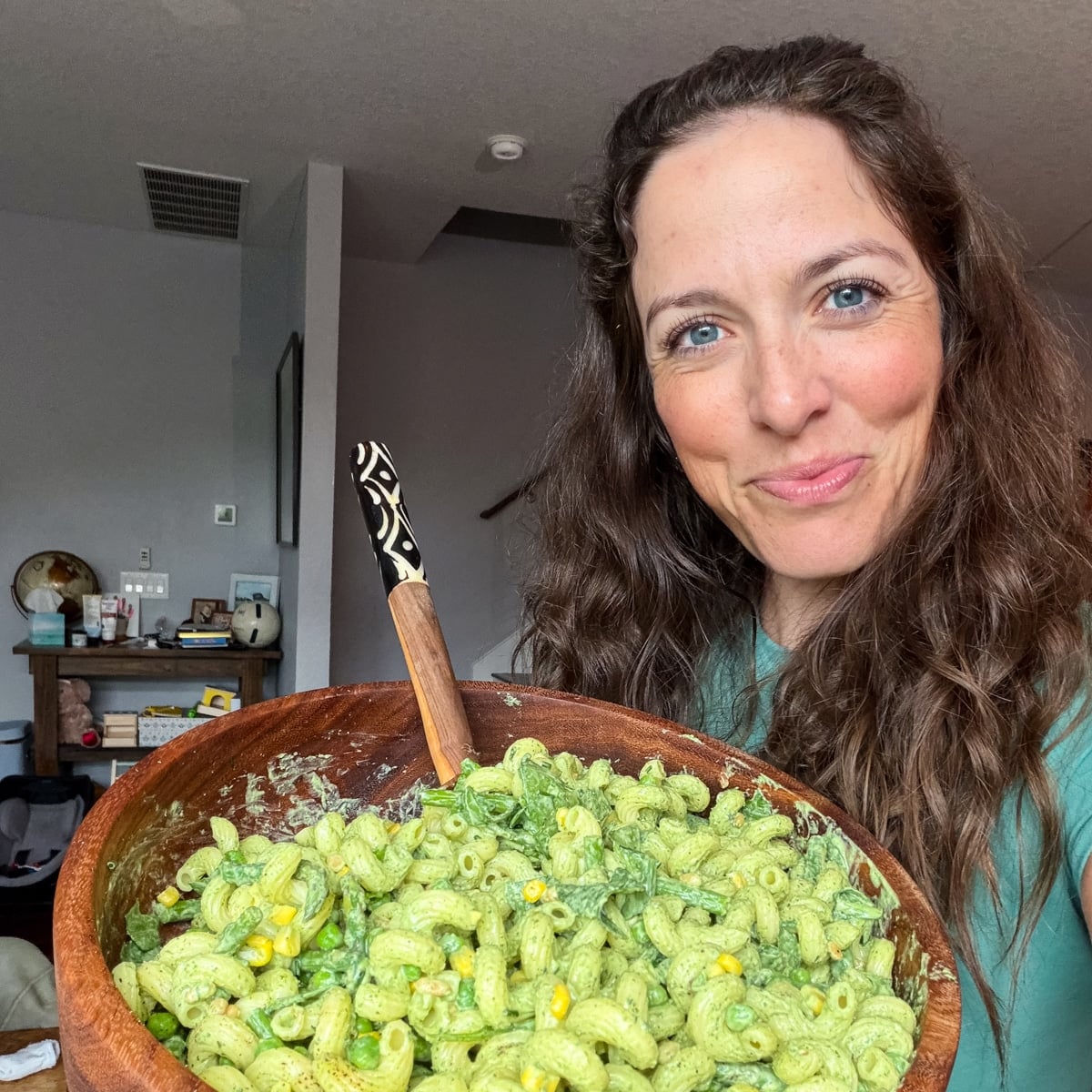 London Lea is holding a serving bowl full of Green Goddess Pasta Salad in her Austin, Texas home.