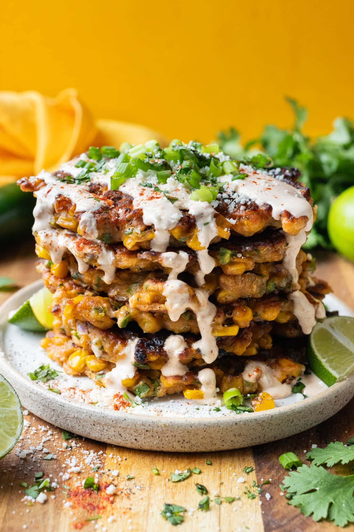 Crispy fried Mexican street corn fritters are in a stick with a crema sauce on top.