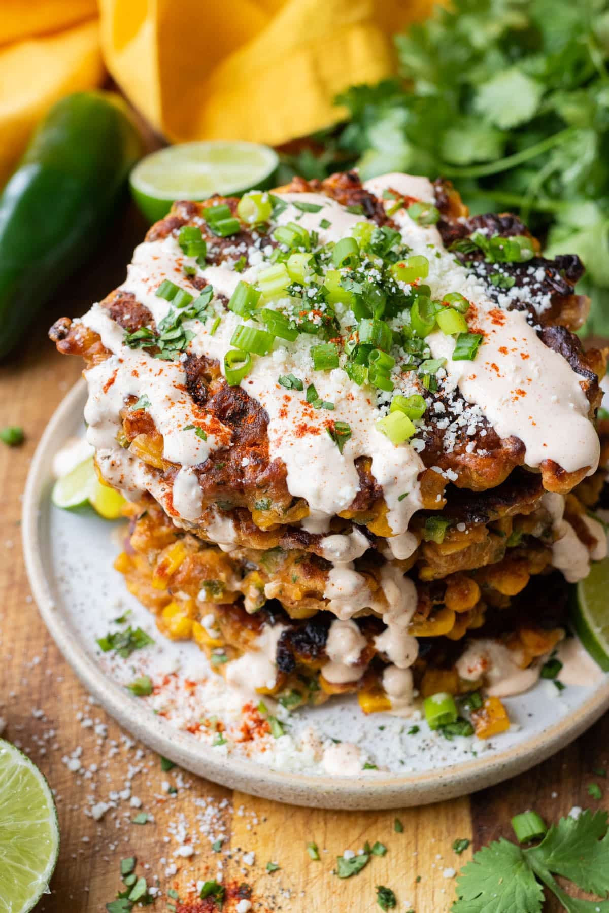 Chili-lime crema is drizzled on top elote corn fritters before serving.