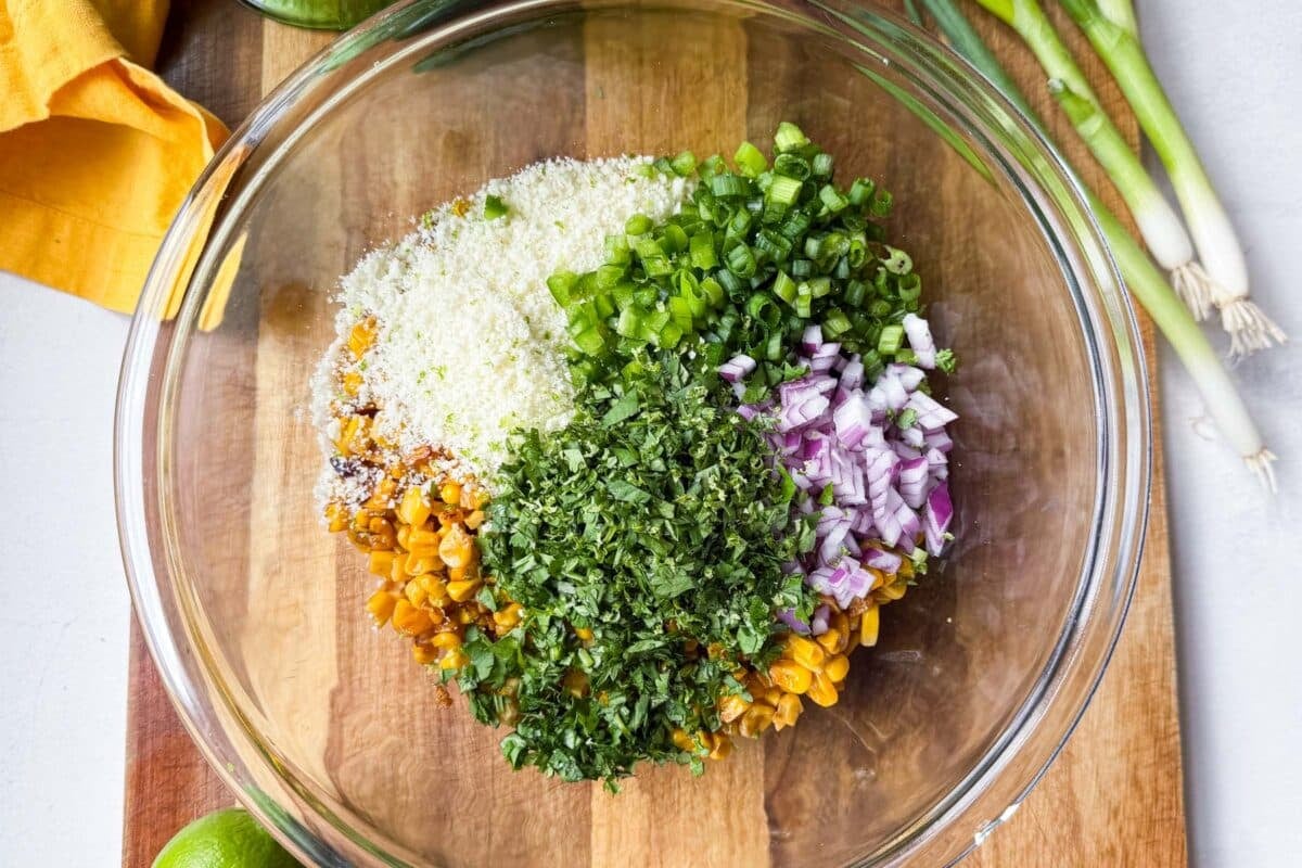 Jalapenos, cilantro, red onions, corn, and cotija cheese are in a bowl.