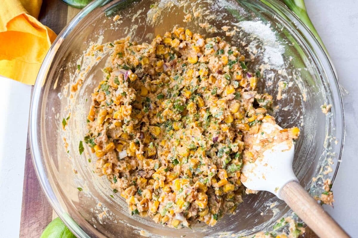 A Mexican street corn fritter recipe batter is mixed together in a bowl.