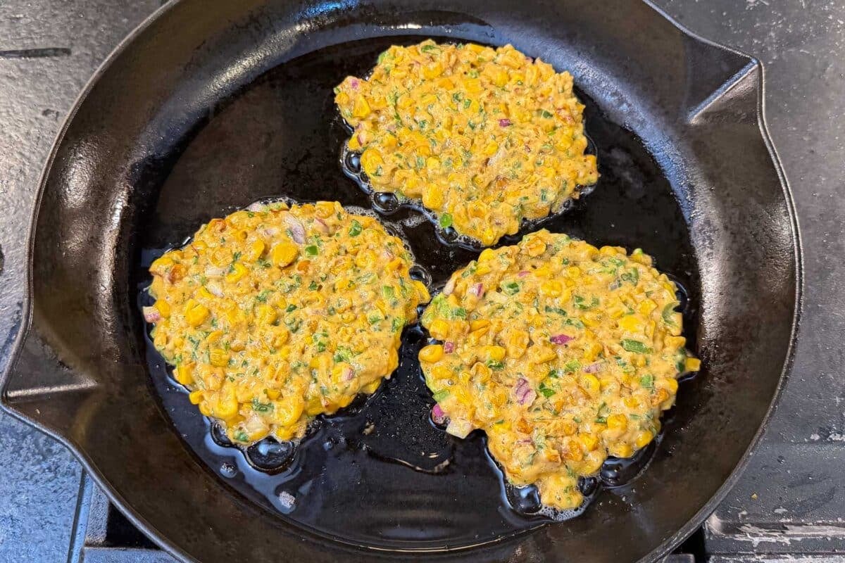 Mexican street corn fritters are cooked in a skillet until crispy.