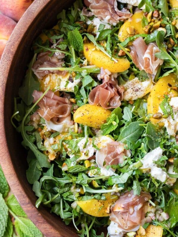 A Peach burrata salad with arugula and pistachios is served with a hot honey vinaigrette.