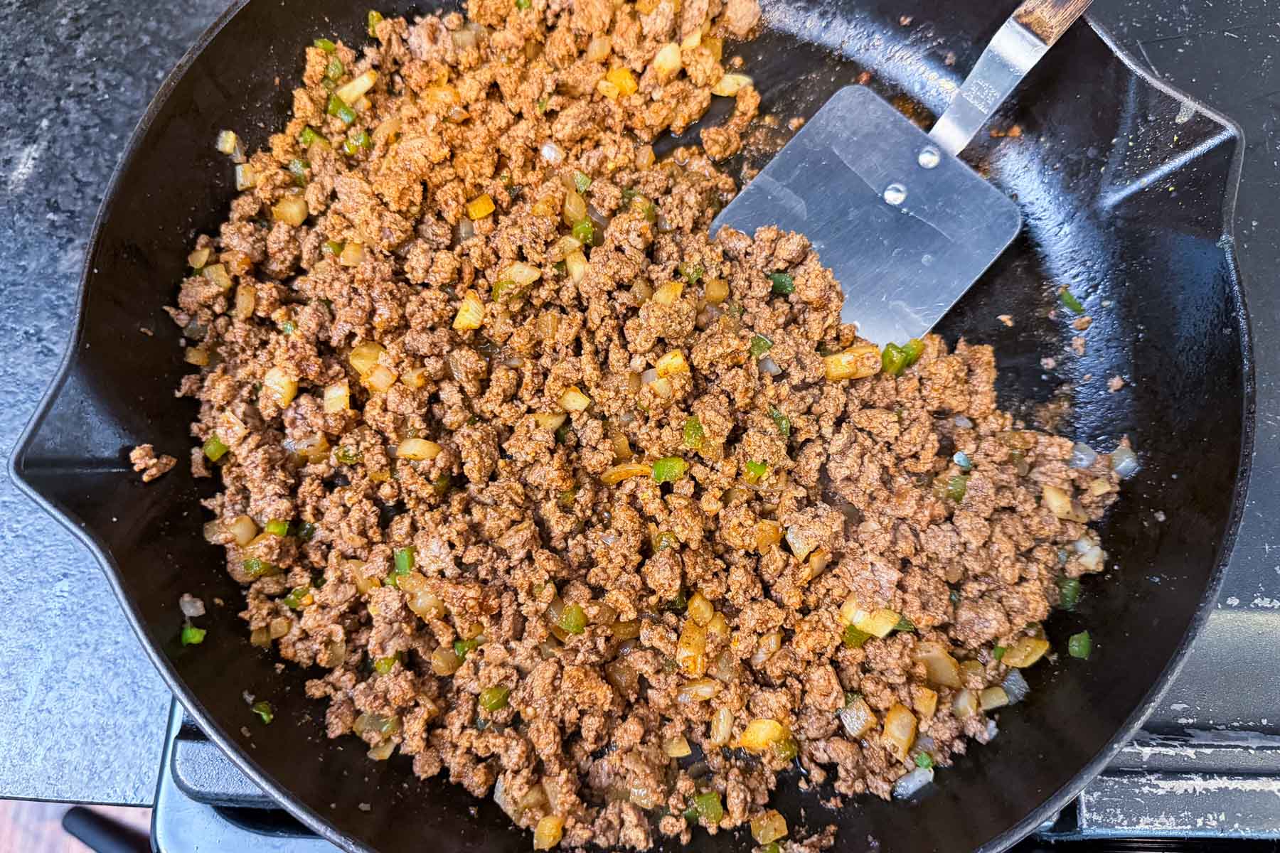 Finished ground beef taco meat in a skillet with a metal spatula.
