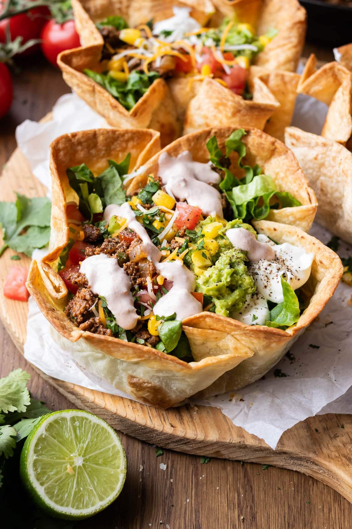 Bubbly taco salad bowls with seasoned ground beef taco meat are served with a simple salsa crema and tons of fresh veggies.