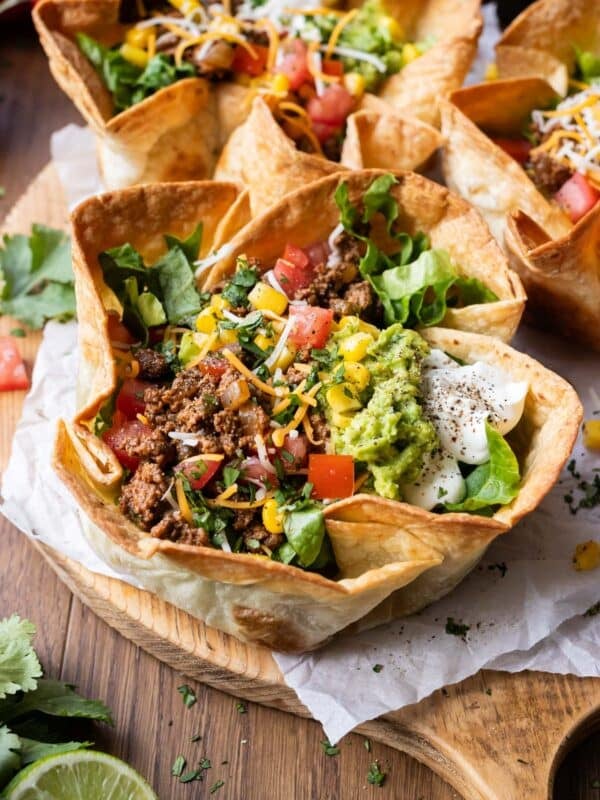 A taco salad bowl with a crispy and bubbly taco salad shell is filled with ground beef taco meat, cheese, tomatoes, and other fresh toppings for an easy dinner.