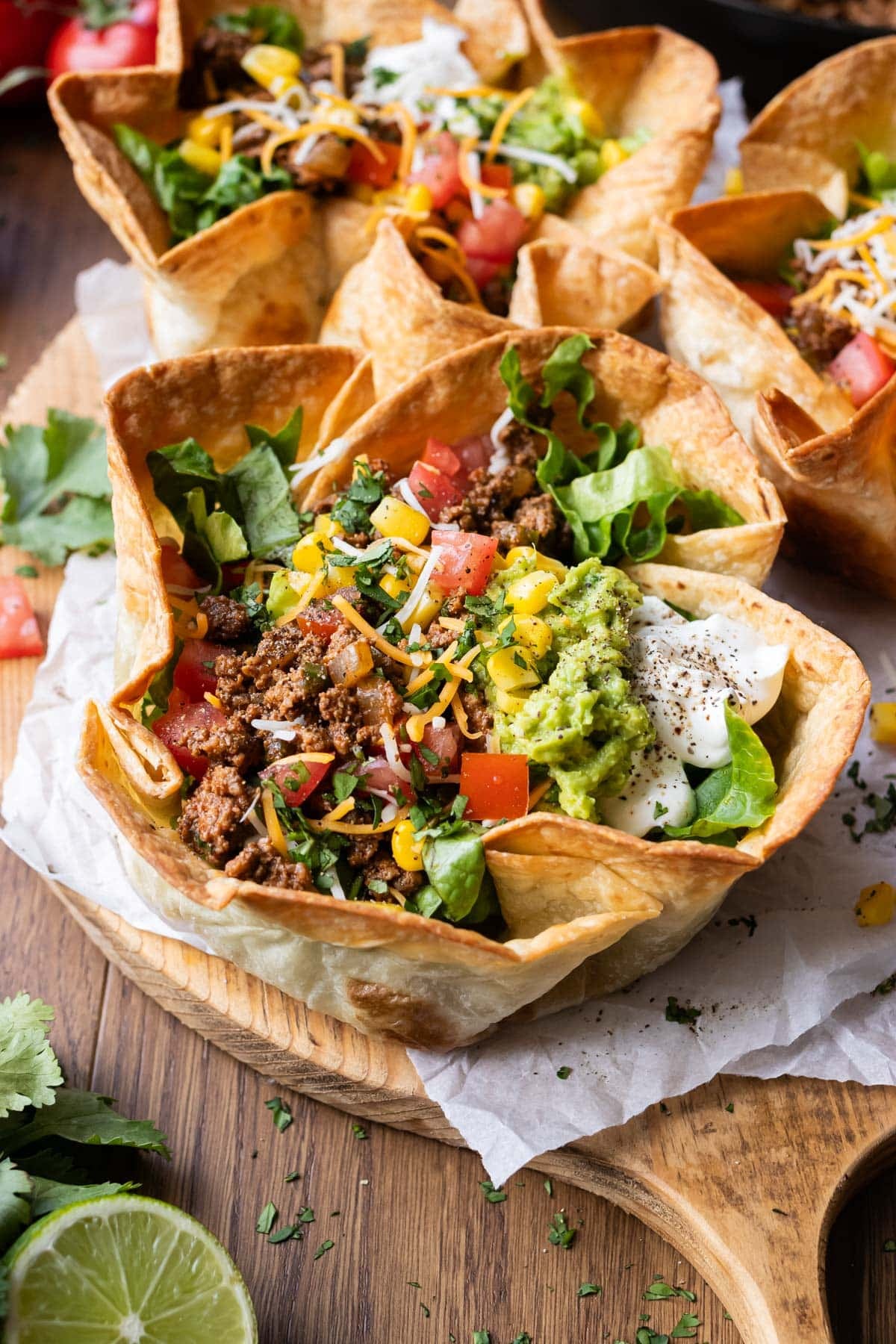A taco salad bowl with a crispy and bubbly taco salad shell is filled with ground beef taco meat, cheese, tomatoes, and other fresh toppings for an easy dinner.