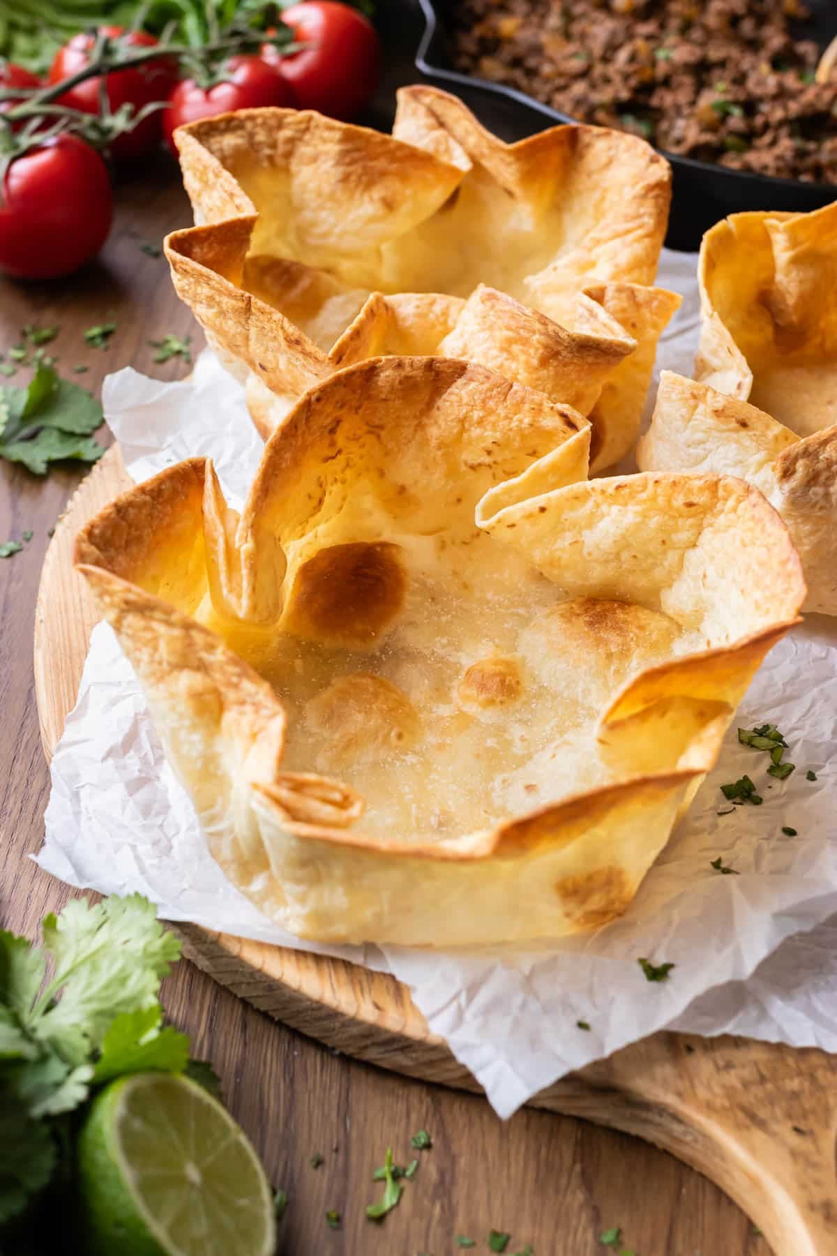 Bubbly taco salad shells are on a serving tray before being loaded up with a taco salad with groun taco meat.